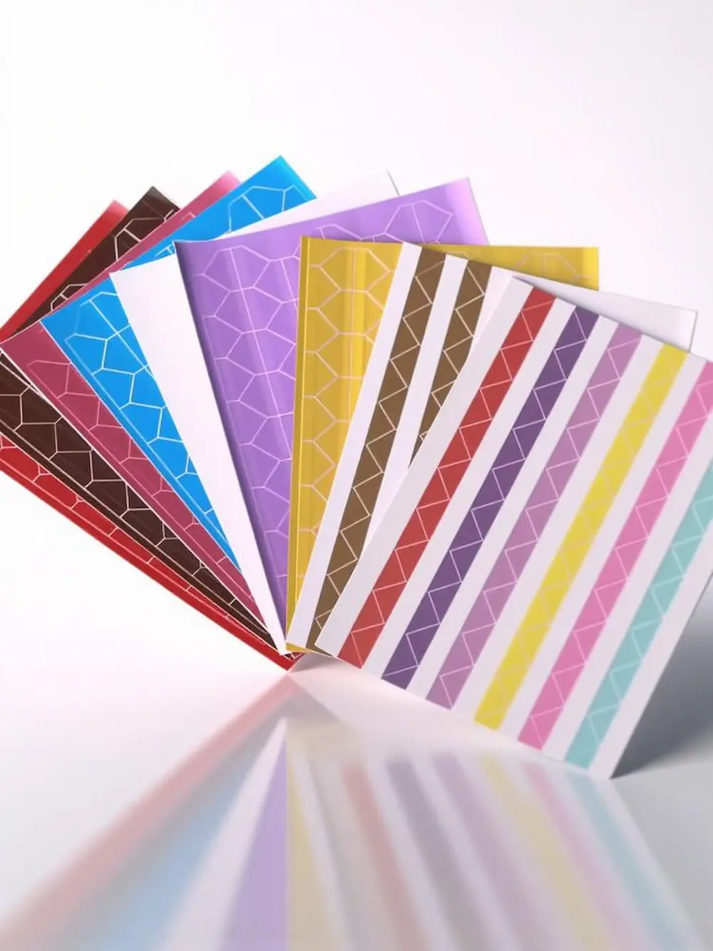 Uma coleção de folhas de cantoneiras para fotos decorativas em várias cores e padrões, disposta em leque.