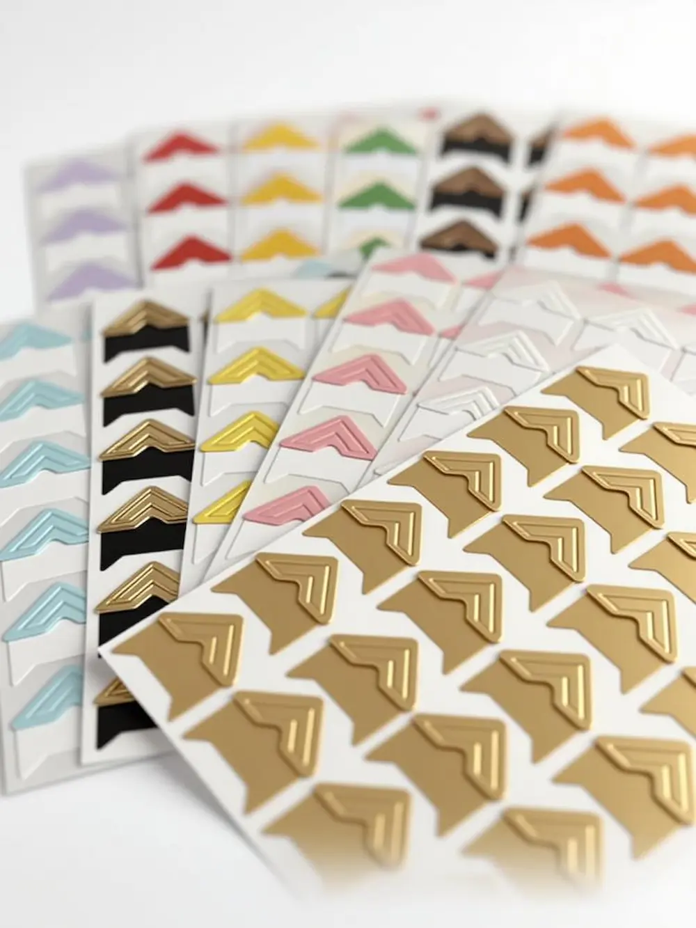 Folhas de cantoneiras para fotos autoadesivas premium nas cores dourada, preta e branca.